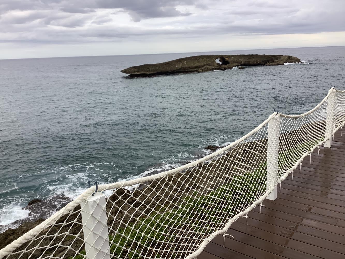 Rope railing on the deck with sea arch islet beyond